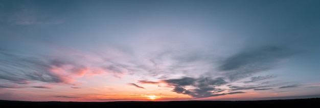 Panorama al tramonto con nuvole di lampone su uno sfondo di cielo blu