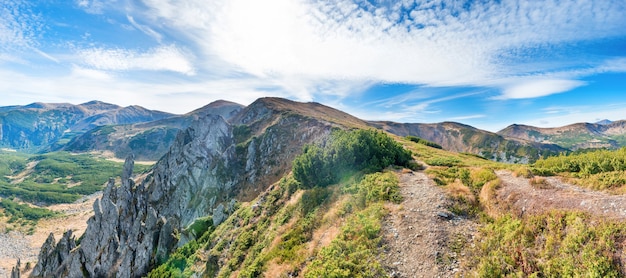 Panorama con paesaggio di montagne, rocce, erba secca e cielo blu