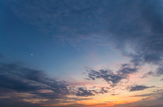 Panorama del cielo all'alba o al tramonto. La bella vista delle nuvole blu scuro si è illuminata dal sole giallo arancio luminoso sul chiaro cielo. Bellezza e potere della natura, meteorologia e concetto di cambiamento climatico.