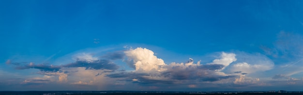 Panorama del cielo azzurro mattutino, illuminato dalla luce solare arancione e rossa, alba colorata.