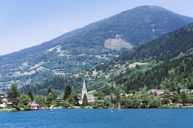 Panorama del lago Feld am See in Carinzia, Austria. Paesaggio con laghetto e cielo blu in primavera o in estate. Scenario nelle Alpi verdi d'Europa. Campagna con montagne alpine. La natura con l'acqua