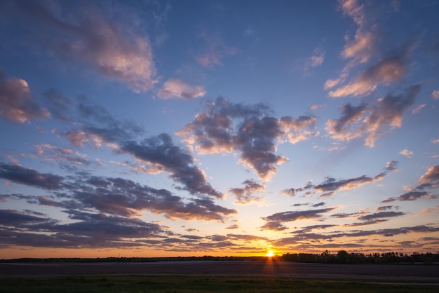 Panorama del tramonto sul campo agricolo nuvole luminose illuminate dagli ultimi raggi del sole nel cielo