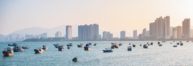 Panorama della città di Nha Trang, famosa destinazione turistica in Vietnam per espatriati russi. Baia di Nha Trang con le barche che galleggiano sull'oceano. Hotel dei grattacieli di tramonto sulla spiaggia.