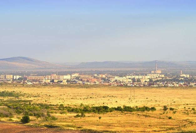 Panorama della città in una foschia tra le colline sotto un cielo nuvoloso blu. Siberia, Russia