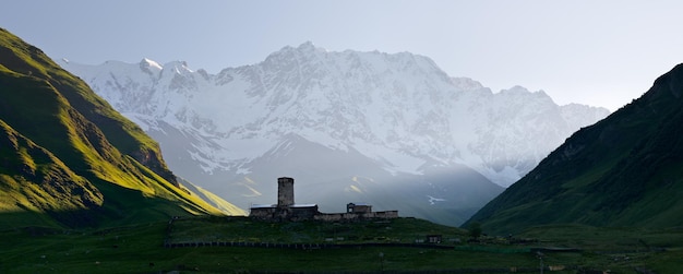 Panorama delle montagne del Caucaso. Chiesa medievale in pietra in una valle di montagna. Veduta del monte Shhara. Comunità di Ushguli, Zemo Svaneti, Georgia