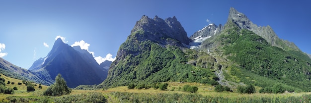 Panorama delle montagne del Caucaso con picchi rocciosi e foresta verde