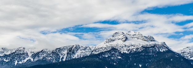 Panorama di alte montagne coperte da neve nuvoloso cielo blu british columbia canada