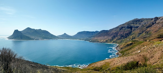 Panorama grandangolare della costa di montagna contro il cielo blu chiaro in Sud Africa Paesaggio panoramico della catena montuosa dei Dodici Apostoli vicino a un oceano calmo nella baia di Hout Posizione popolare per escursioni dall'alto