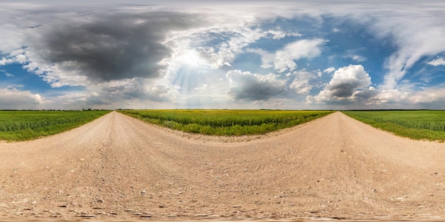 Panorama hdri sferico completo senza soluzione di continuità Vista angolare a 360 gradi su strada sterrata tra i campi in una giornata estiva con fantastiche nuvole prima della tempesta in proiezione equirettangolare per contenuti di realtà virtuale VR AR