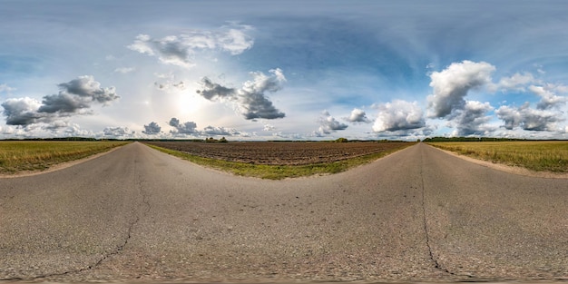 Panorama hdri sferico completo senza soluzione di continuità Vista angolare a 360 gradi sulla vecchia strada asfaltata tra i campi in una giornata autunnale con fantastiche nuvole in proiezione equirettangolare pronte per contenuti di realtà virtuale VR AR