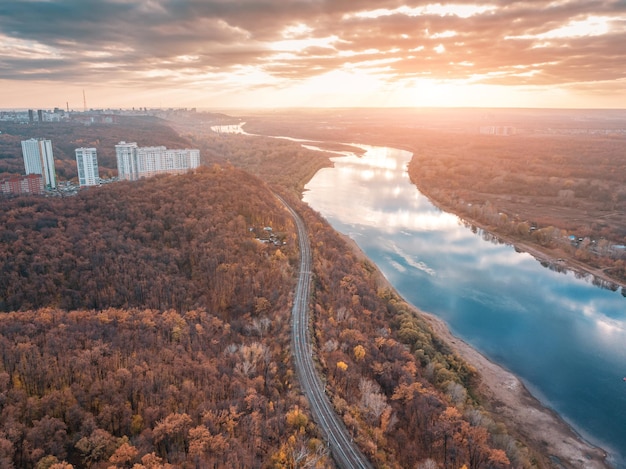 Panorama panoramico aereo della ferrovia alla periferia della città Maestose nuvole al tramonto che si riflettono nelle acque del fiume