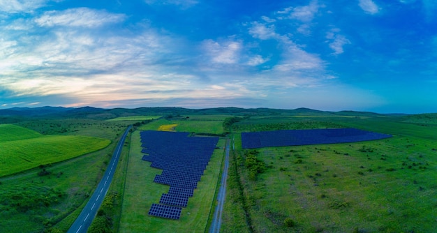 Panorama su pannelli solari per generare energia dai raggi solari sono installati nei prati sotto un cielo azzurro con sole