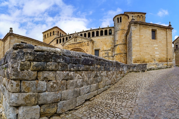 Panoramica della vecchia chiesa romanica in pietra con pavimentazione in ciottoli e cielo blu