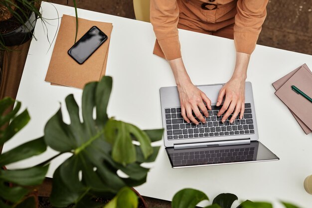 Panoramica delle mani di una giovane donna d'affari o studente che digita sulla tastiera del laptop dalla scrivania mentre si lavora sulla presentazione