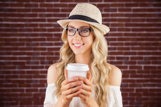 Pantaloni a vita bassa biondi sorridenti splendidi che tengono tazza asportabile