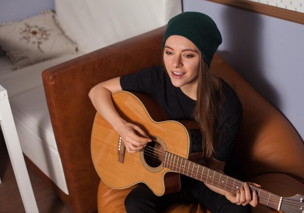 Pantaloni a vita bassa della donna che giocano sulla chitarra e cantano