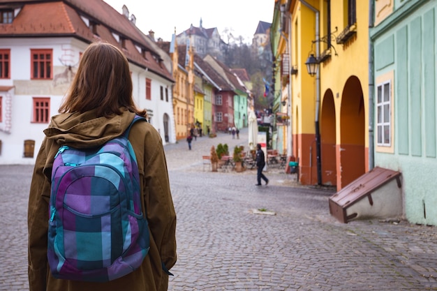 Pantaloni a vita bassa della ragazza che camminano alla bella via nella vecchia città di Sighisoara, Romania