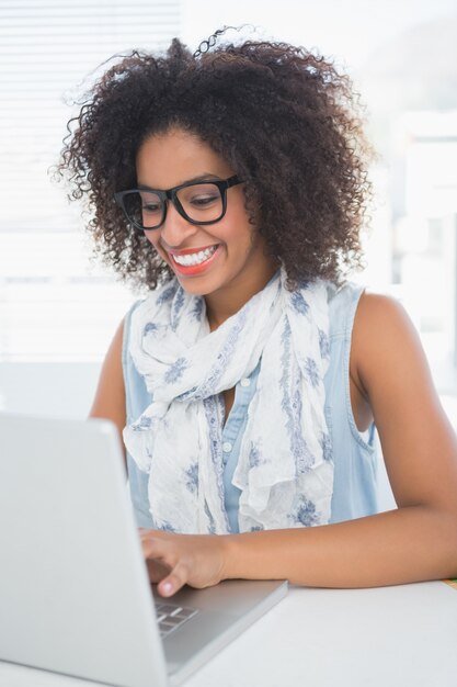 Pantaloni a vita bassa graziosi che lavorano al suo scrittorio con il computer portatile