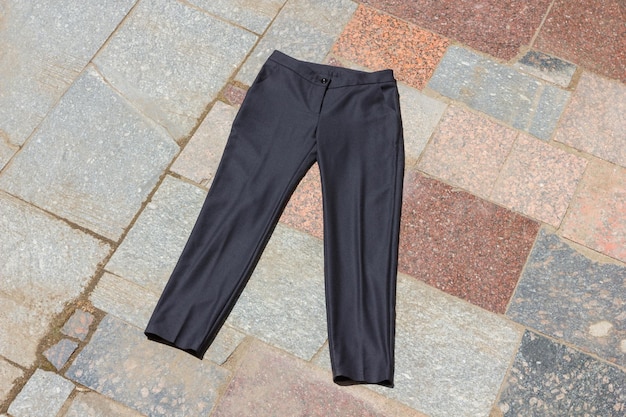 Pantaloni da uomo neri giacciono sul vecchio portico Pantaloni scuri realizzati in tessuto naturale su sfondo grigio Abbigliamento da uomo su sfondo naturale abiti sartoriali per un negozio