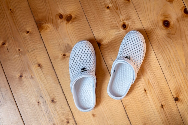 Pantofole da casa in poliuretano bianco sul pavimento in legno