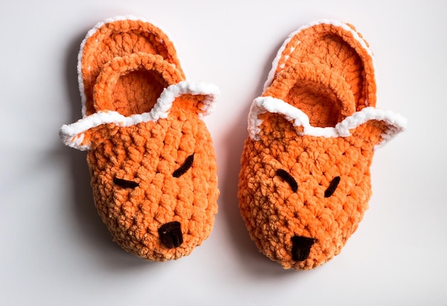 Pantofole in peluche a forma di volpe su sfondo bianco Pantofole lavorate a maglia per bambini