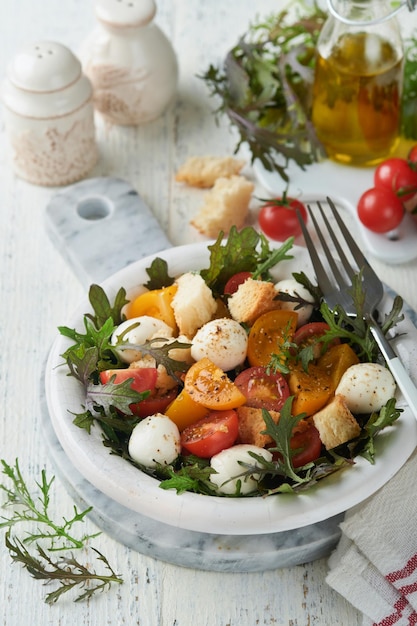 Panzanella toscana Cherry Tomato insalata con arugula basilico mozzarella e biscotti su ciotola bianca Tradizionale insalata italiana Mediterraneo cibo sano e cucina