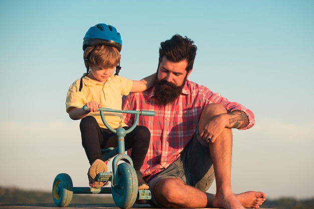 Papà aiuta suo figlio ad andare in bicicletta Padre adorabile che insegna al figlio ad andare in bicicletta