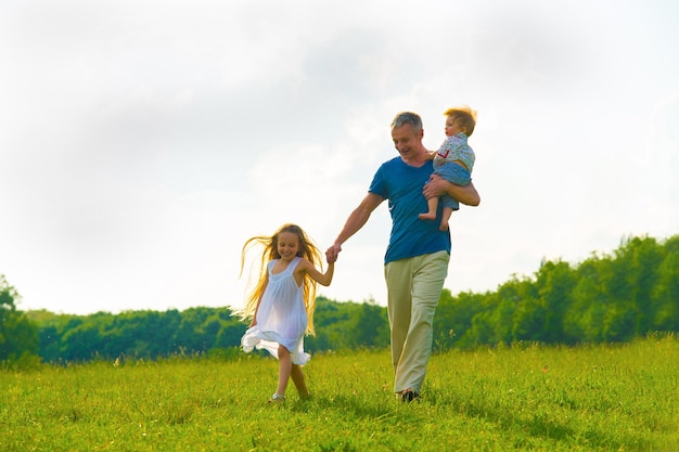 Papà con bambini che camminano sul prato vacanze in famiglia