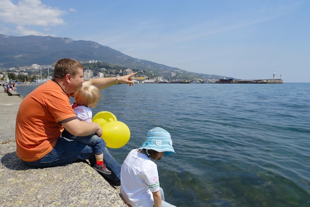 Papà con due figlie sedute in riva al mare