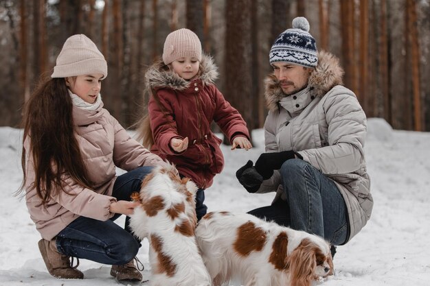 Papà con figlie e cani cammina e gioca nel passatempo familiare della foresta invernale