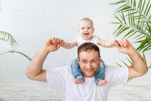 Papà con il figlio al collo che si diverte su uno sfondo bianco, paternità felice e famiglia, festa del papà