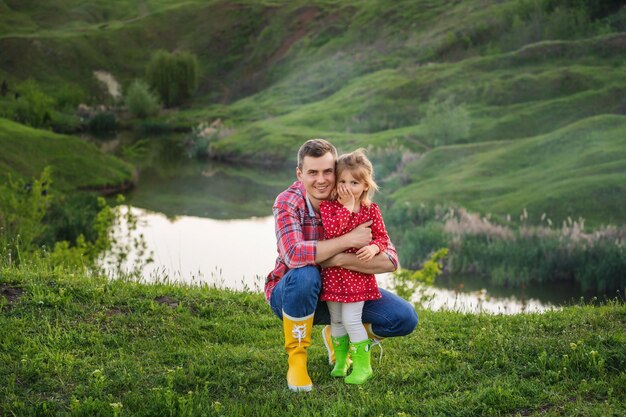 Papà con la sua piccola figlia carina trascorrono del tempo insieme all'aperto vicino al lago