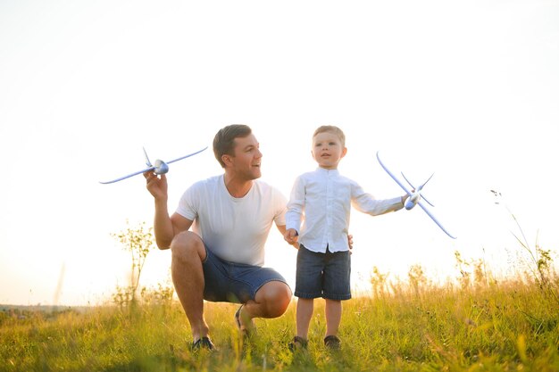 Papà con suo figlio al tramonto nella natura Un padre gioca con gli aeroplani giocattolo con suo figlio al tramonto della festa del papà