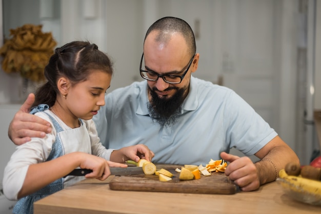 Papà dà da mangiare a una ragazza una banana in cucina, Cibo per bambini. Bacche e frutti.