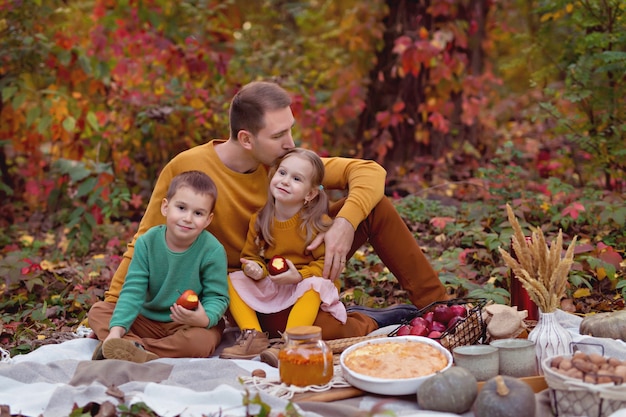 Papà di famiglia felice, figlio piccolo, figlia in autunno picnic con torta, zucca, tè