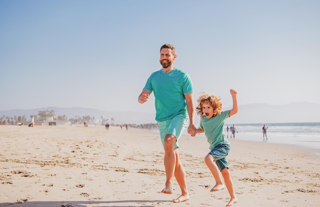 Papà e bambino che si divertono all'aperto padre e figlio che corrono sul mare infanzia e concetto di genitorialità