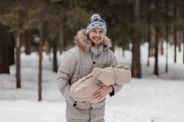 Papà e bambino stanno camminando lungo la foresta Papà tiene in braccio un bambino in inverno Papà e figlia all'aperto in inverno