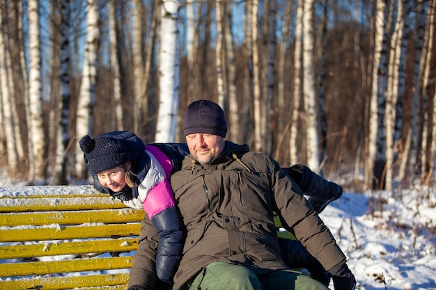 Papà e figlia si siedono su una panchina in un parco invernale