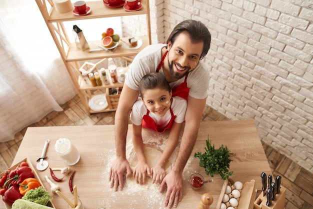 Papà e figlia stanno rotolando fuori pasta sulla cucina