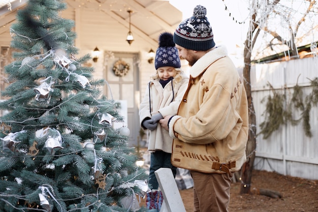 Papà e figlia vestono l'albero di Natale in inverno