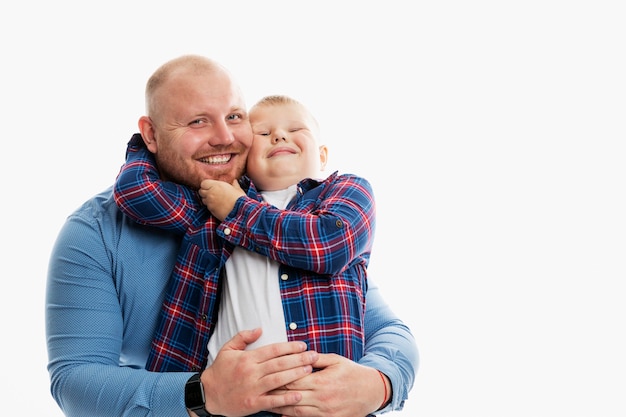 Papà e figlio, 6-7 anni, si abbracciano e ridono. Relazioni familiari felici, amore e tenerezza. Sfondo bianco. Spazio per il testo.