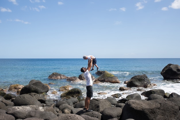 Papà e figlio che camminano lungo la riva dell'oceano. Fine settimana al mare. Una pietra da spiaggia.