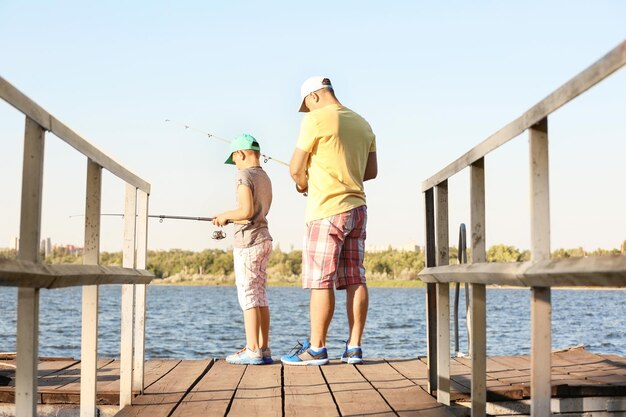 Papà e figlio che pescano dal molo sul fiume