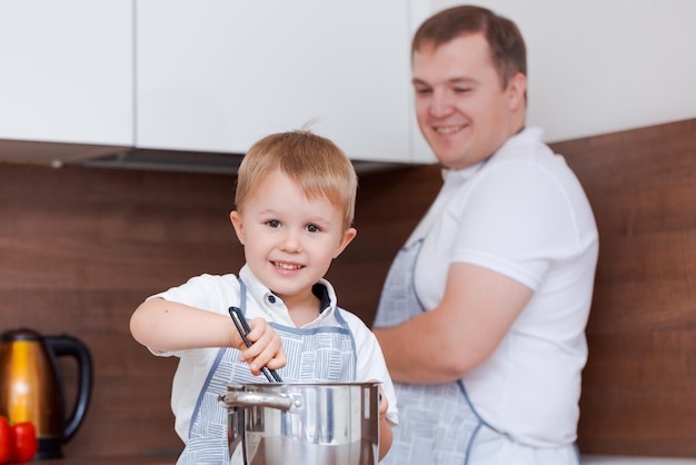 Papà e figlio cucinano insieme in cucina a preparare il cibo divertendosi a casa