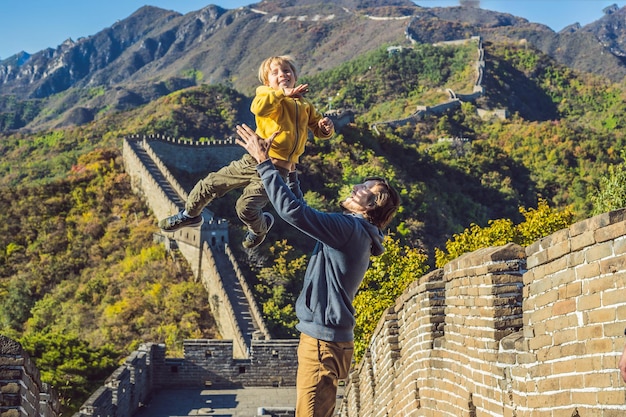 Papà e figlio di turisti gioiosi allegri felici alla grande muraglia cinese divertendosi in viaggio sorridendo