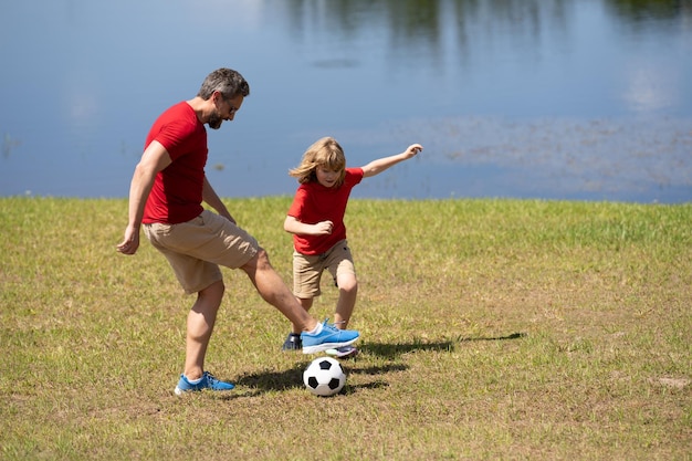 Papà e figlio giocano a calcio insieme sul prato verde padre e figlio si divertono sul campo da calcio da