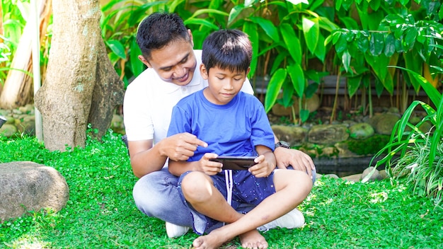 Papà e figlio giocano con il cellulare nel parco