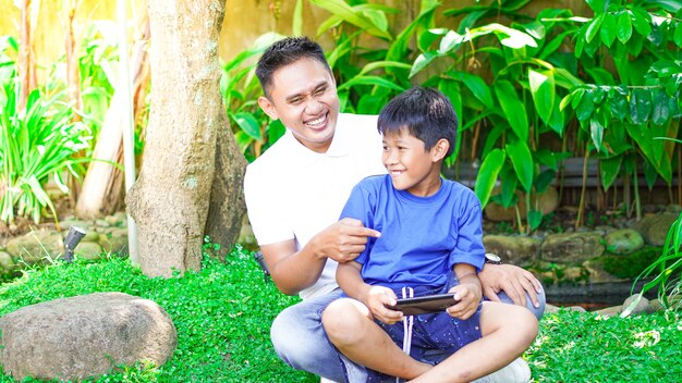 Papà e figlio giocano con il cellulare nel parco