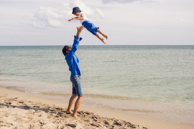 Papà e figlio giocano sulla spiaggia vomitano in estate in abiti blu mentre sono in vacanza