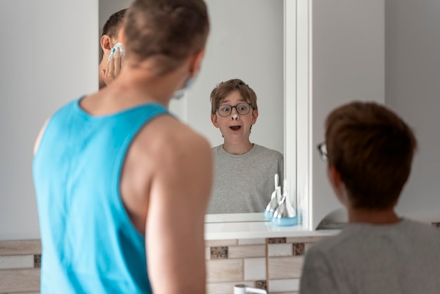 Papà e figlio in bagno davanti allo specchio Padre e figlio si radono insieme in bagno